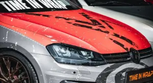 Close-up of a car wrapped in a red and white vinyl graphic with distressed patterns