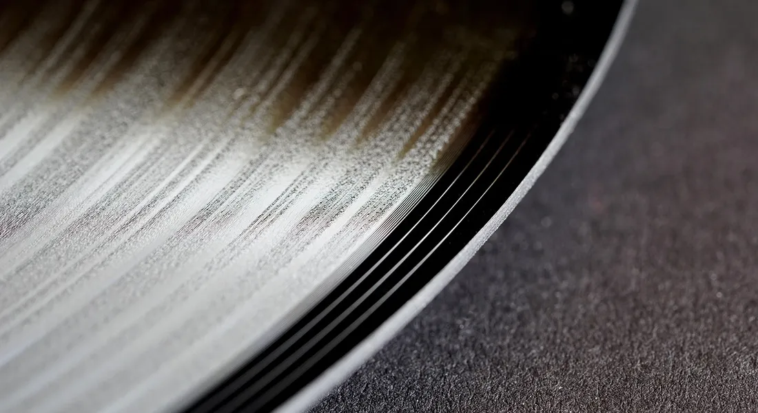 Close-up view of vinyl wrap with brushed metallic texture along a curved edge