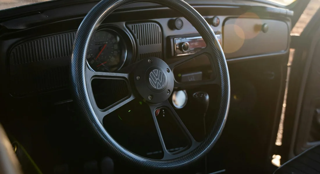 Close-up of a classic Volkswagen steering wheel inside a car interior, highlighting the textured steering wheel and dashboard.