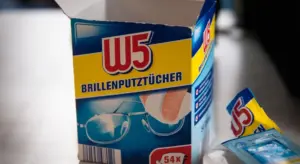 W5 Brillenputztücher box (glasses cleaning wipes) with blue and yellow packaging, and a microfiber cloth partially visible