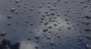 Close-up of water droplets on a glossy black car paint surface.