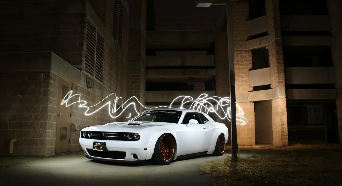 White sports car in an industrial night setting with light trails swirling around it.