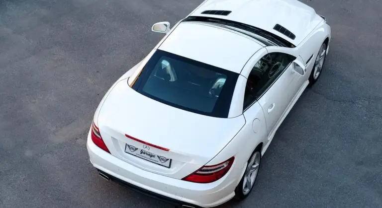 Top-down view of a white luxury car parked on a paved surface, showing the roof, windows, and rear end.