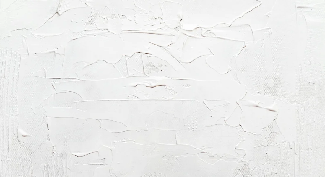 Close-up of white textured wall with peeling paint and cracks to illustrate surface deterioration and the importance of preventive protection.