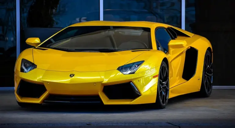 Bright yellow Lamborghini sports car parked outside a glass storefront