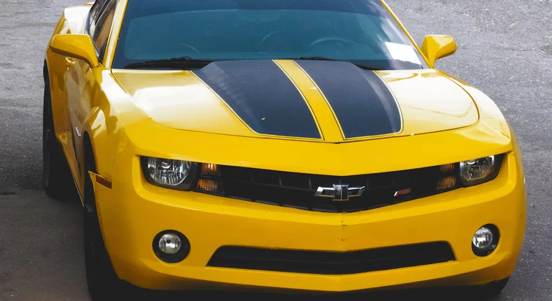 Front view of a bright yellow Chevrolet Camaro with black racing stripes